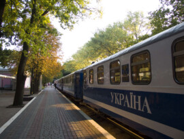 Zug an einem niedlichen kleinen Bahnhof. Auf der Seite steht "Ukraina" Zug mit Ukraina-Schriftzug